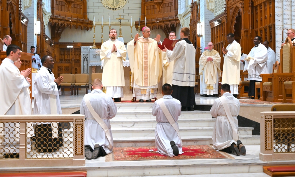Bishop Ruggieri praying the Prayer of Ordination over three men.